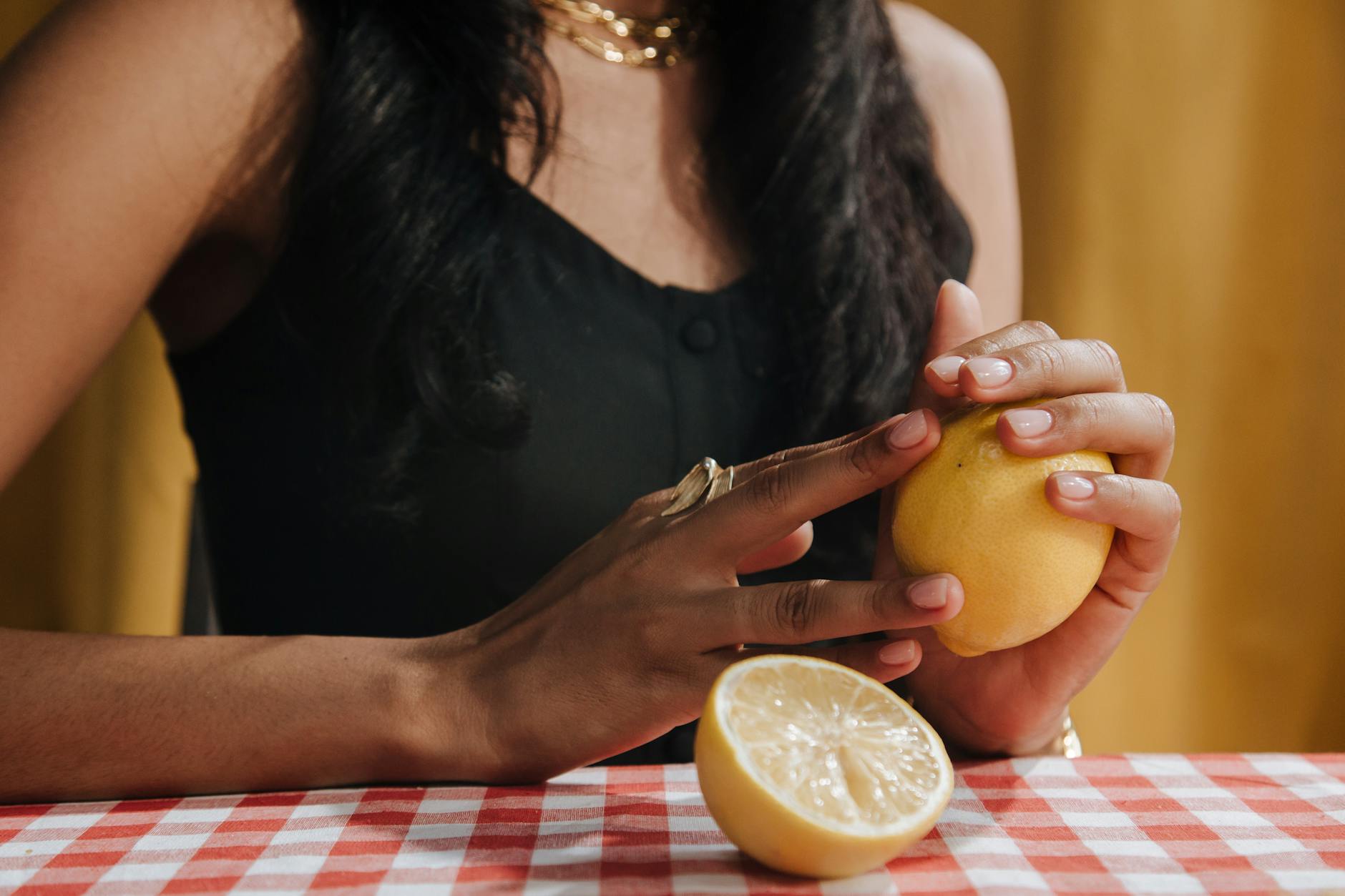 Three fresh lemons on a white plate against a vibrant yellow background