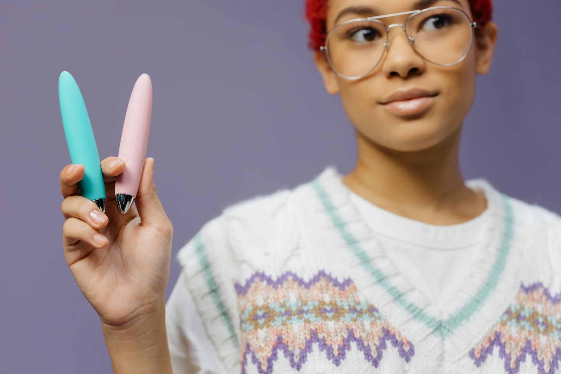 A woman holding a colorful lemon vibrator against a purple background, representing intimate self-discovery.
