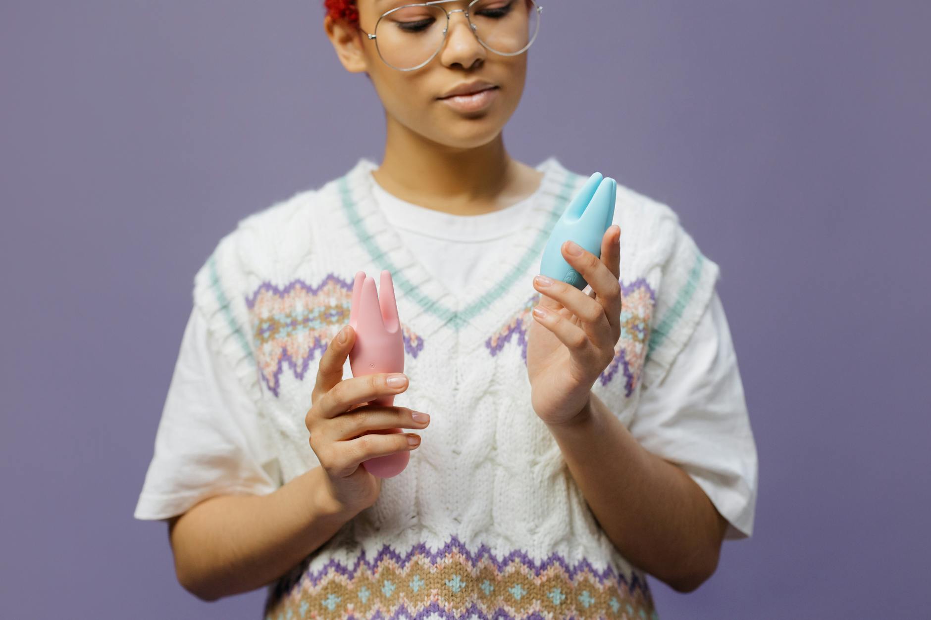 Woman holding blue and pink silicone vibrators in a contemplative moment of self-discovery