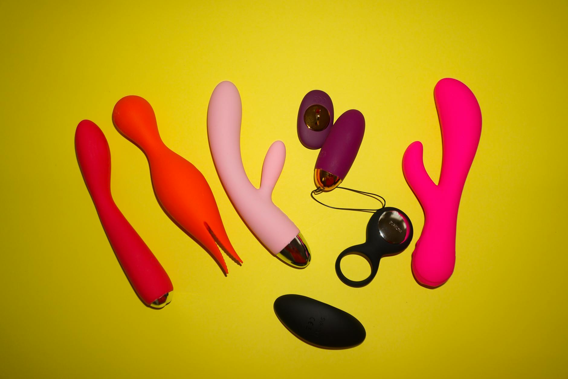 Colorful clitoral vibrators arranged on a bright yellow background, showcasing modern designs for focused pleasure
