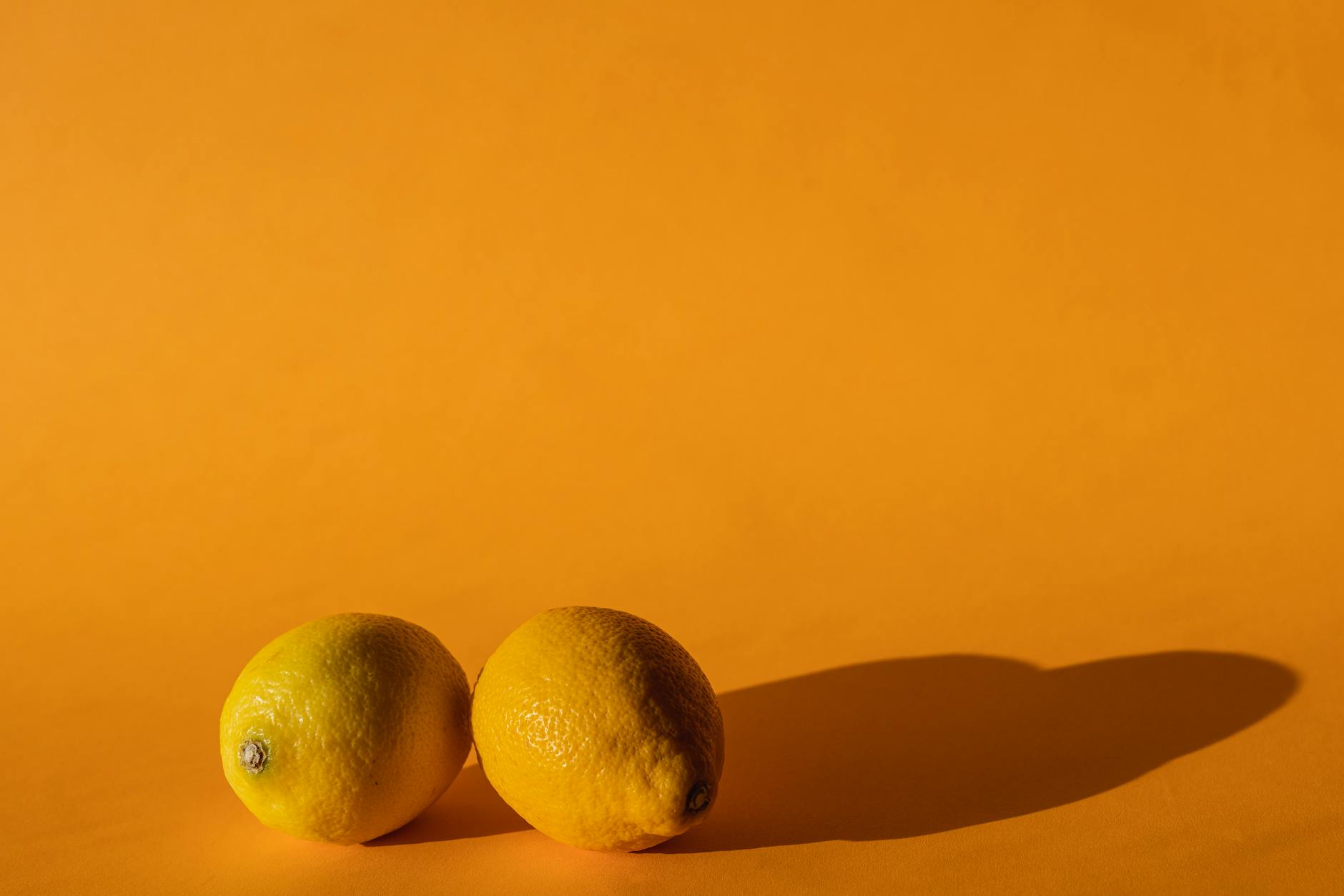 A hand holding a fresh lemon against a bright yellow background, symbolizing freshness and renewal