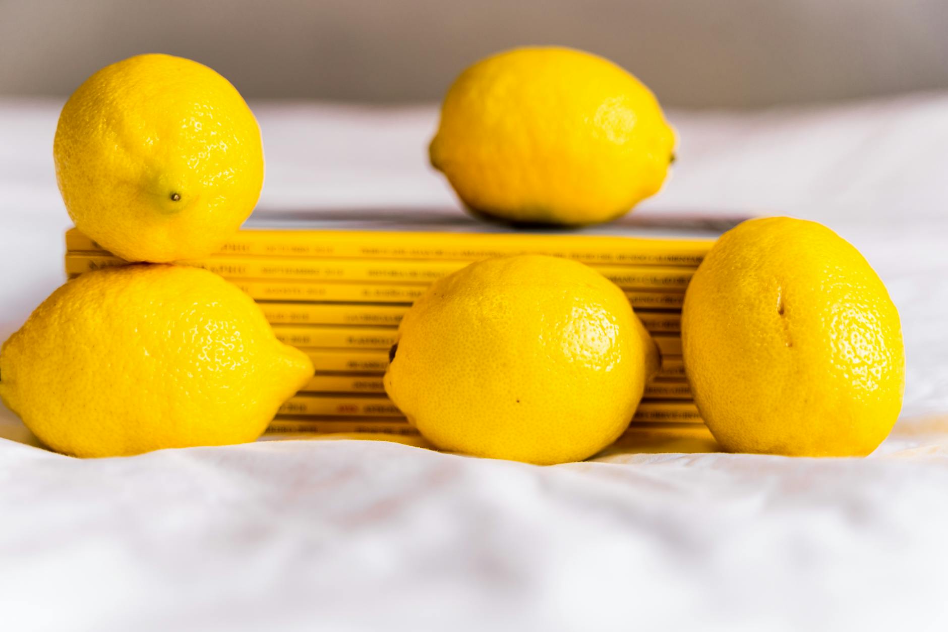 Whole fresh lemons arranged with stacked books on white cloth